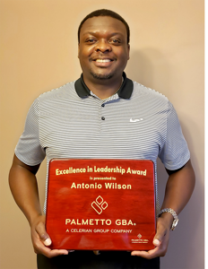 Antonio Wilson standing, holding a plaque